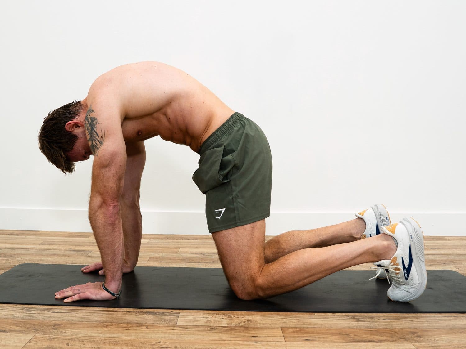 Dan on his hands and knees with his back rounded and chin tucked, the cat position