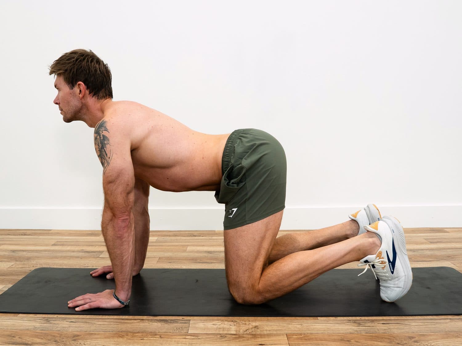 Dan on his hands and knees with his back arched and chest forward, the cow position