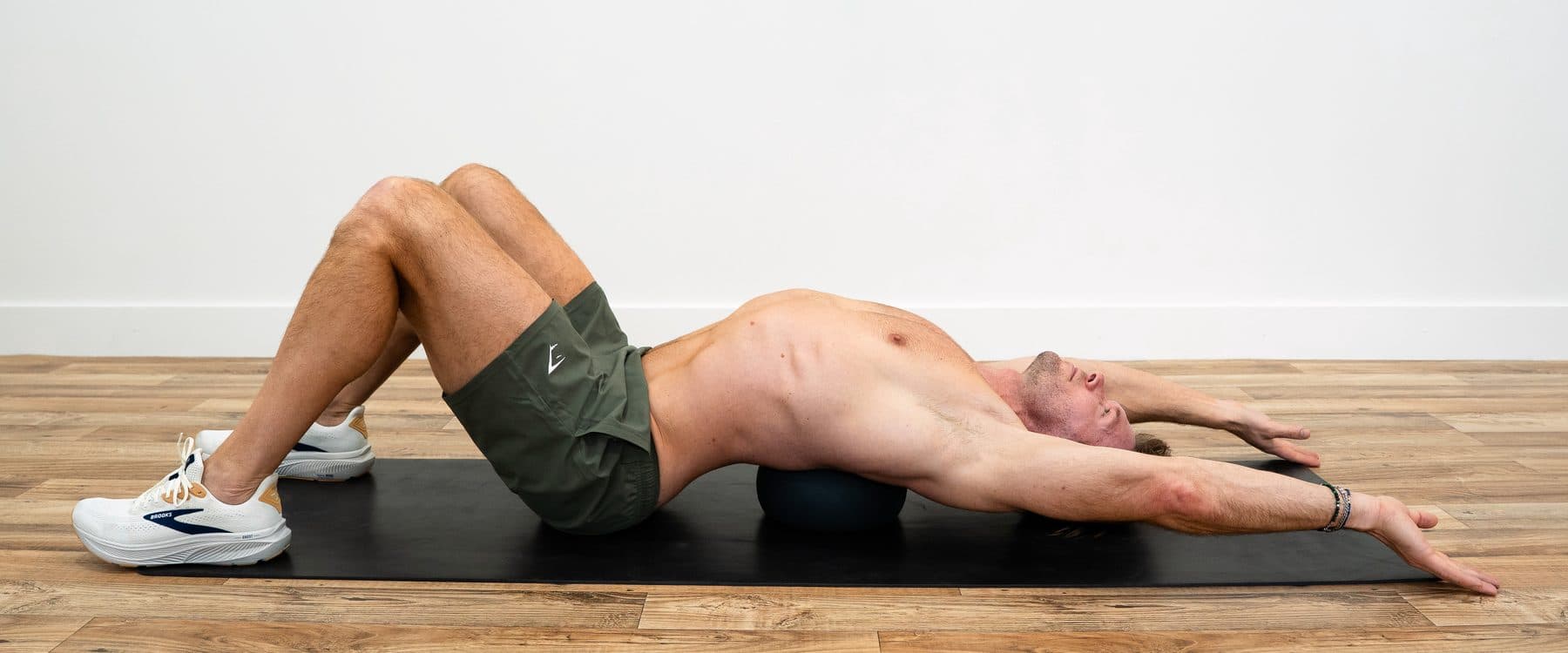 Dan lying back over a medicine ball under his lower back, knees bent, arms reaching overhead
