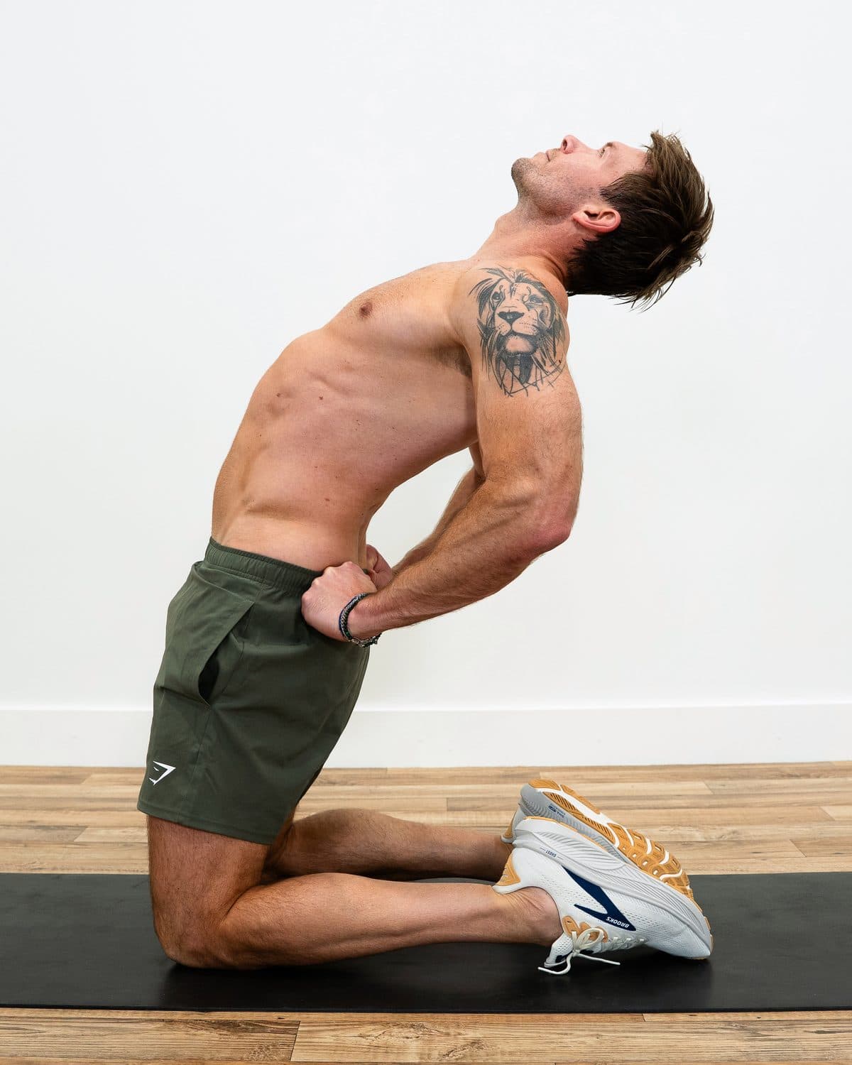 Dan kneeling upright with his hands on his lower back, lifting his chest up and back